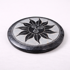 Round stone coaster with sun design on a white background